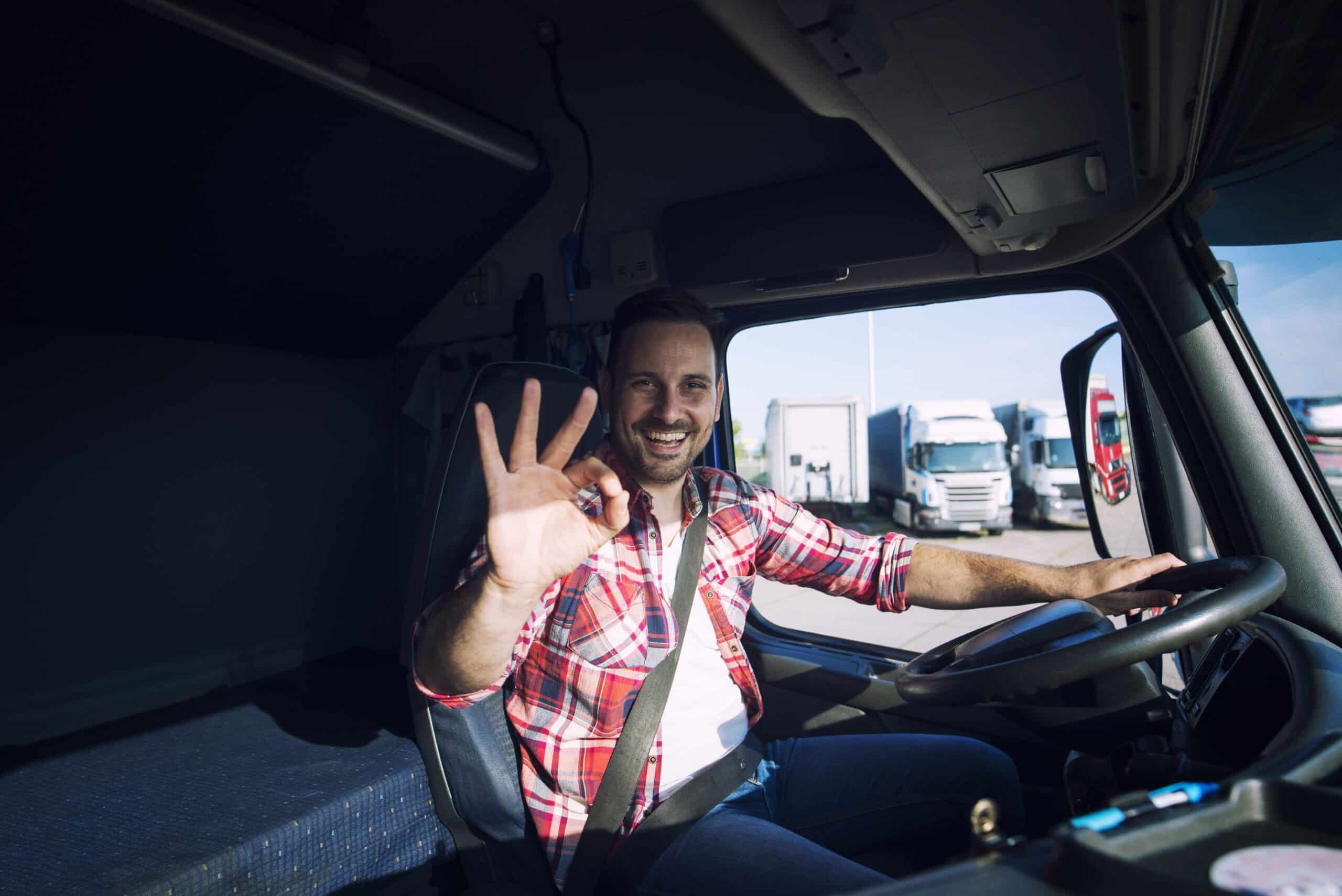 Truck driver loving his job showing okay gesture sign while sitting his truck cabin